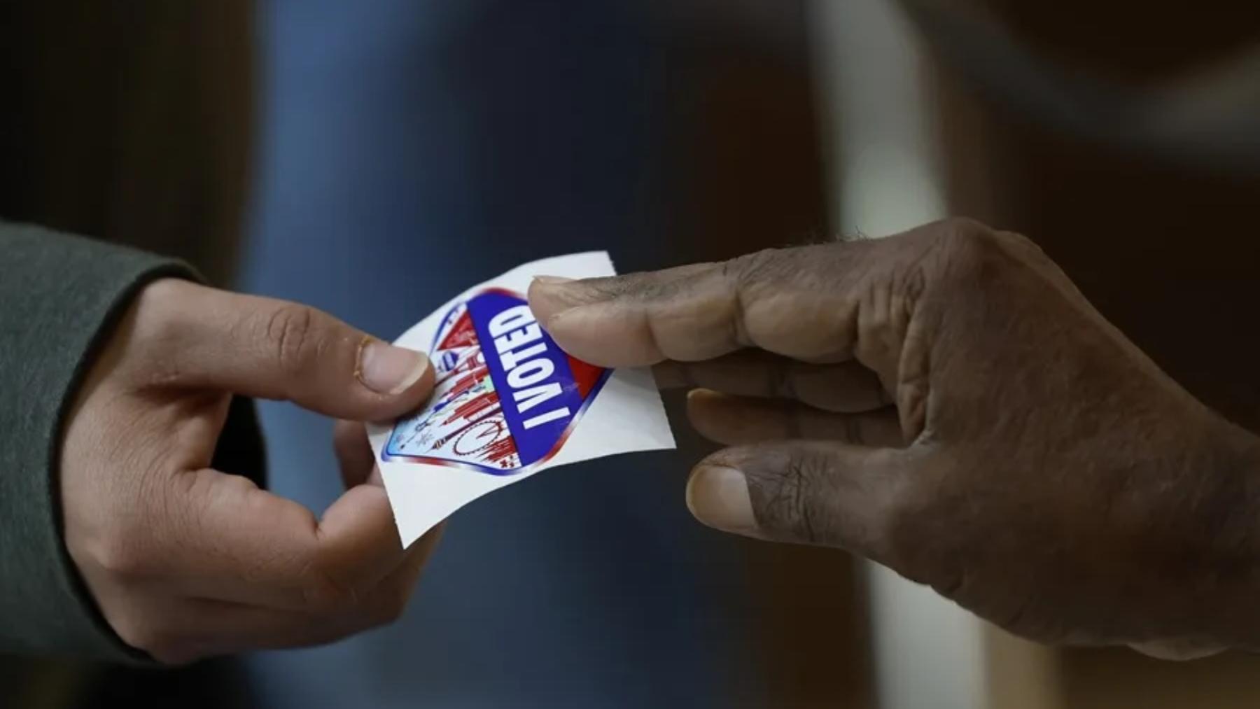 Fotografía de una persona que recibe un distintivo por votar en unas elecciones en Estados Unidos.