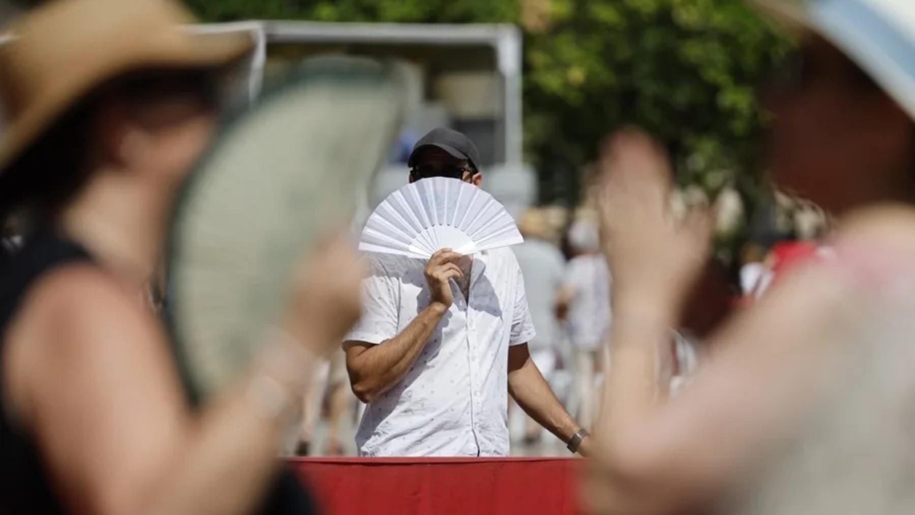 Un viandante se abanica para combatir el calor mientras pasea por Valencia.