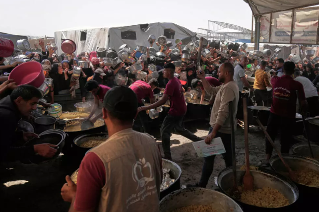 Palestinos luchan por conseguir alimentos donados en un comedor comunitario de Khan Younis, en el sur de la Franja de Gaza, viernes 9 de mayo de 2025. 