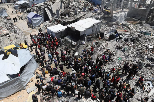 Palestinos esperan para recibir alimentos cocinados por una cocina de caridad, en Beit Lahia, norte de la Franja de Gaza, 8 de mayo de 2025.