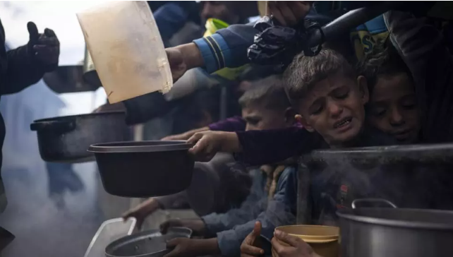 Palestinos, incluidos niños, se forman en una fila, para tratar de recibir alimentos, en Rafah, en el sur de la Franja de Gaza, el 16 de febrero de 2024.