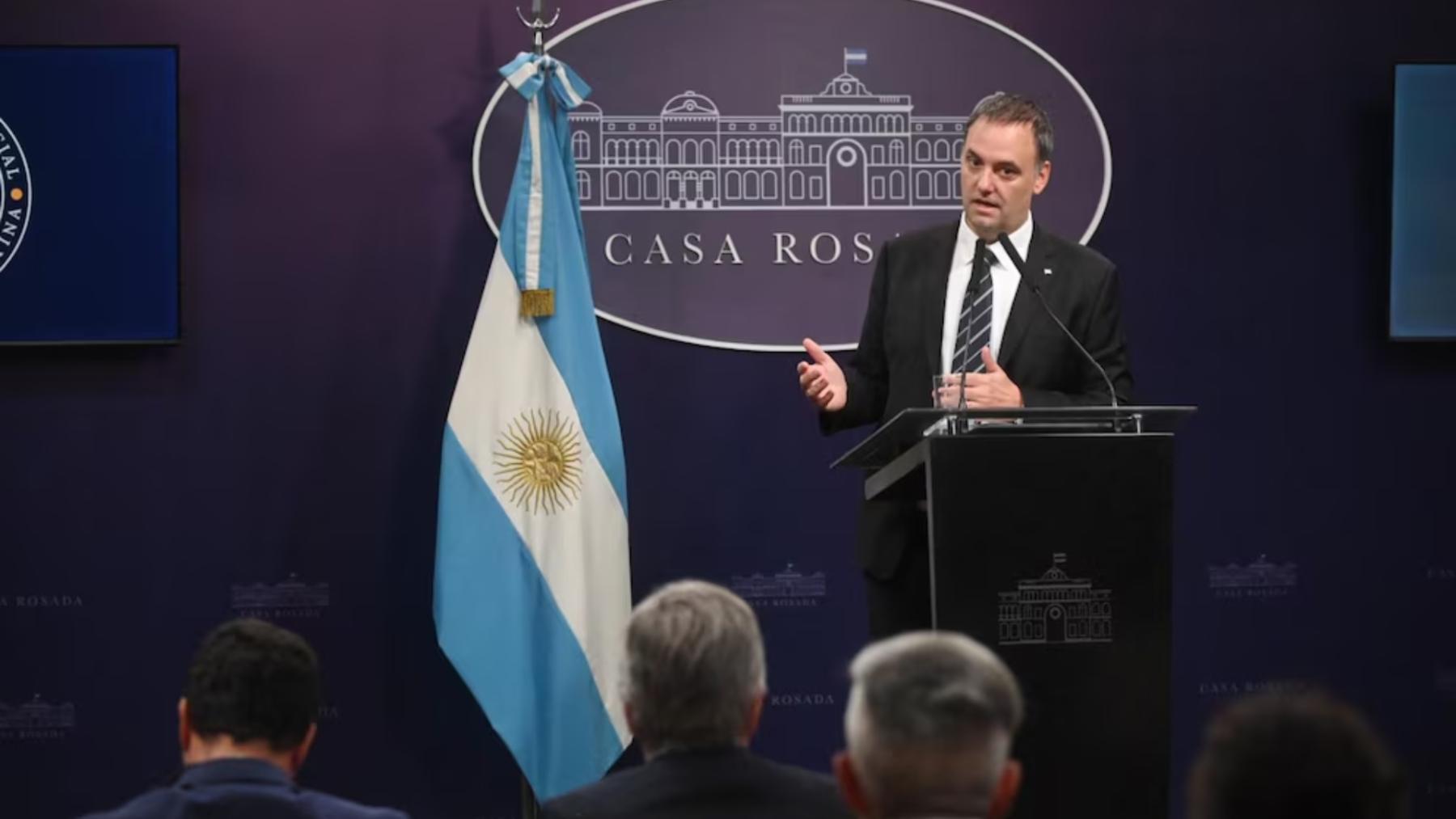 Manuel Adorni habla en conferencia de prensa y en primera fila lo escucha el ministro de Economía, Luis Caputo